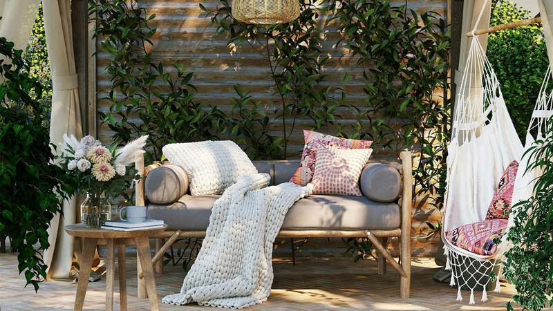 Side view of editor selecting pergola cushions at an outdoor studio setup with cedar pergola overhead